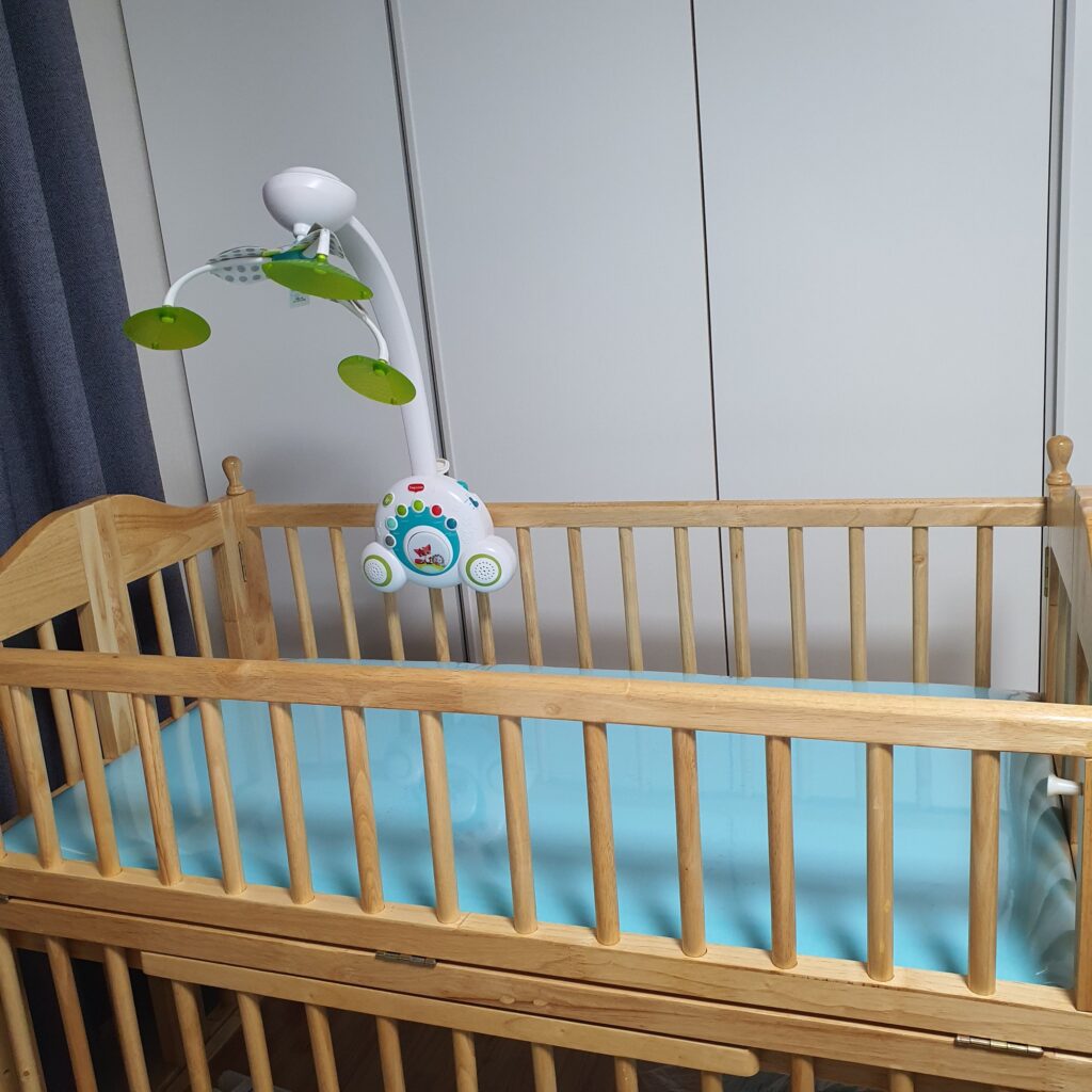 아기 침대에 모빌이 설치되어 있다