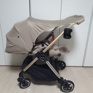 베이지 색상 절충형 유모차의 옆모습 차양막이 펼쳐져 있다