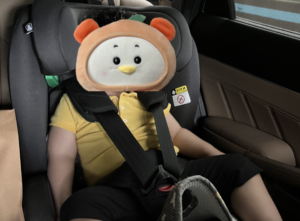 자동차 안에 설치된 토들러 카시트에 앉아있는 노란 상의를 입은 아기 