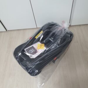 비닐에 쌓인 바구니 카시트가 실내 바닥에 놓여있다